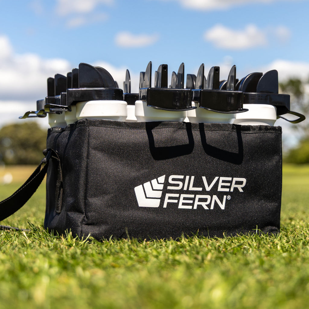 12-Pack Hygiene Bottles With Carrier, Drink Bottles with hygiene caps and chin holder for safe bottle sharing, 12-bottle fabric carrier with removable divider and adjustable carry strap / sling, lifestyle close-up shot, full pack sitting on the grass, lifestyle.