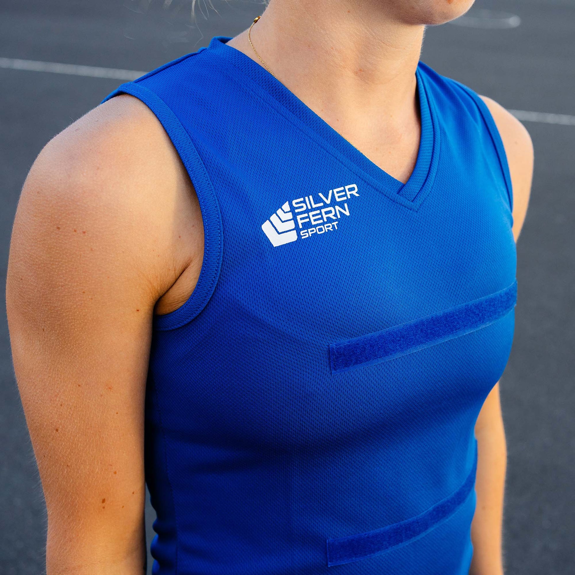 Close-up of a netball player wearing a royal blue dress uniform, focusing on the upper body and the Silver Fern logo on the chest.