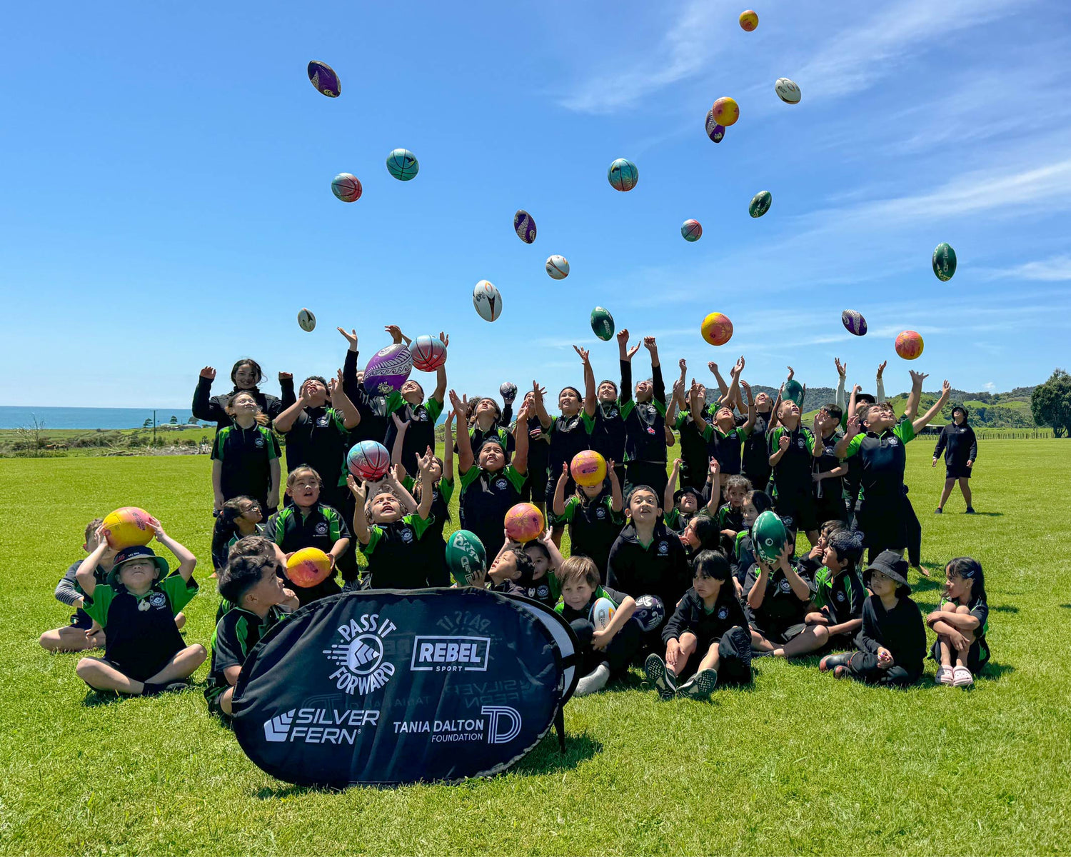 Pass it Forward featured image, school kids throwing pass it forward balls in the air, banner with partners logos, Rebel Sport, Silver Fern, Tania Dalton Foundation