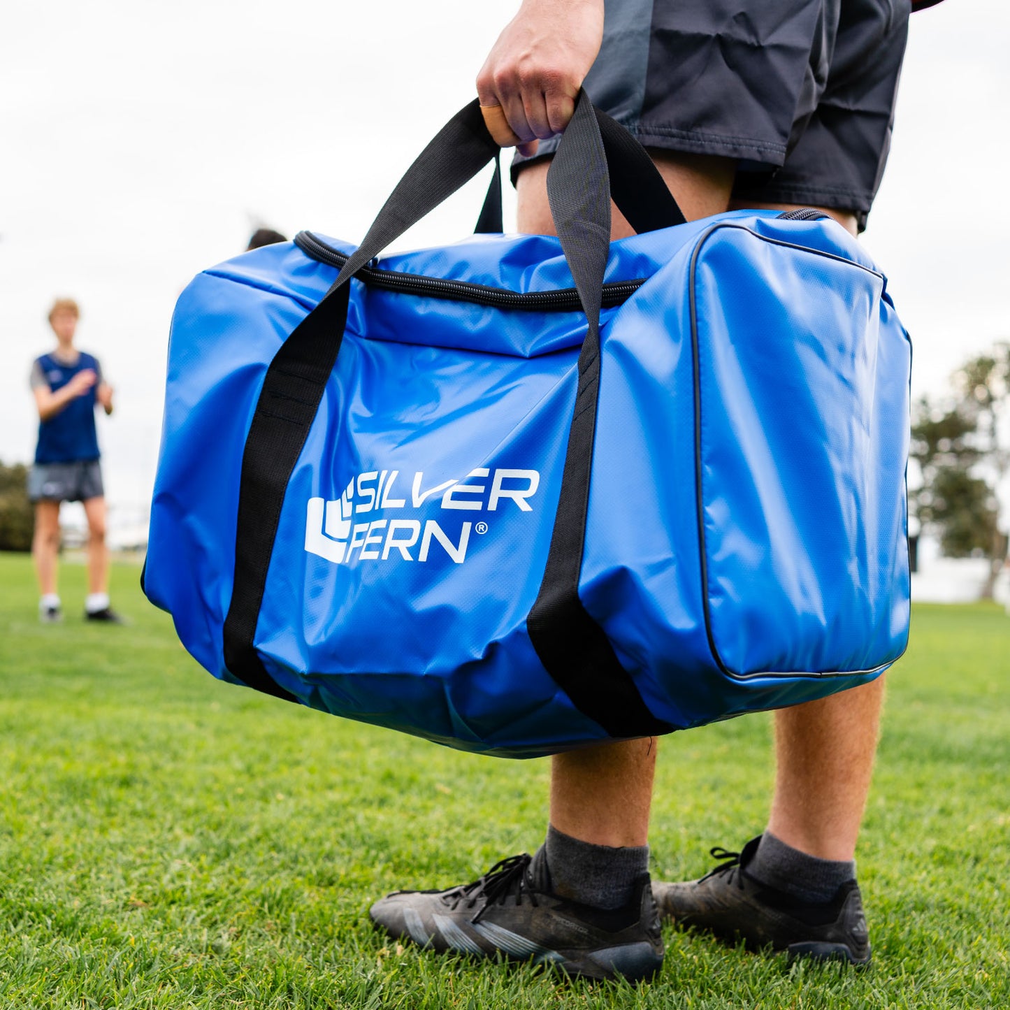 Silver Fern blue PVC gear bag size large, lifestyle shot, rugby player holding the bag