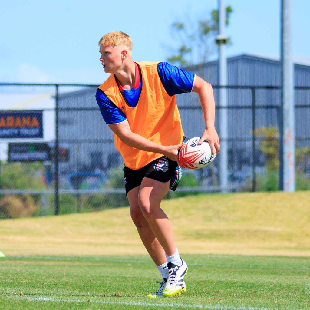 Silver Fern Rugby Premium Trainer Stellar Ball, Red, Size 5, player passing ball in hand, lifestyle.