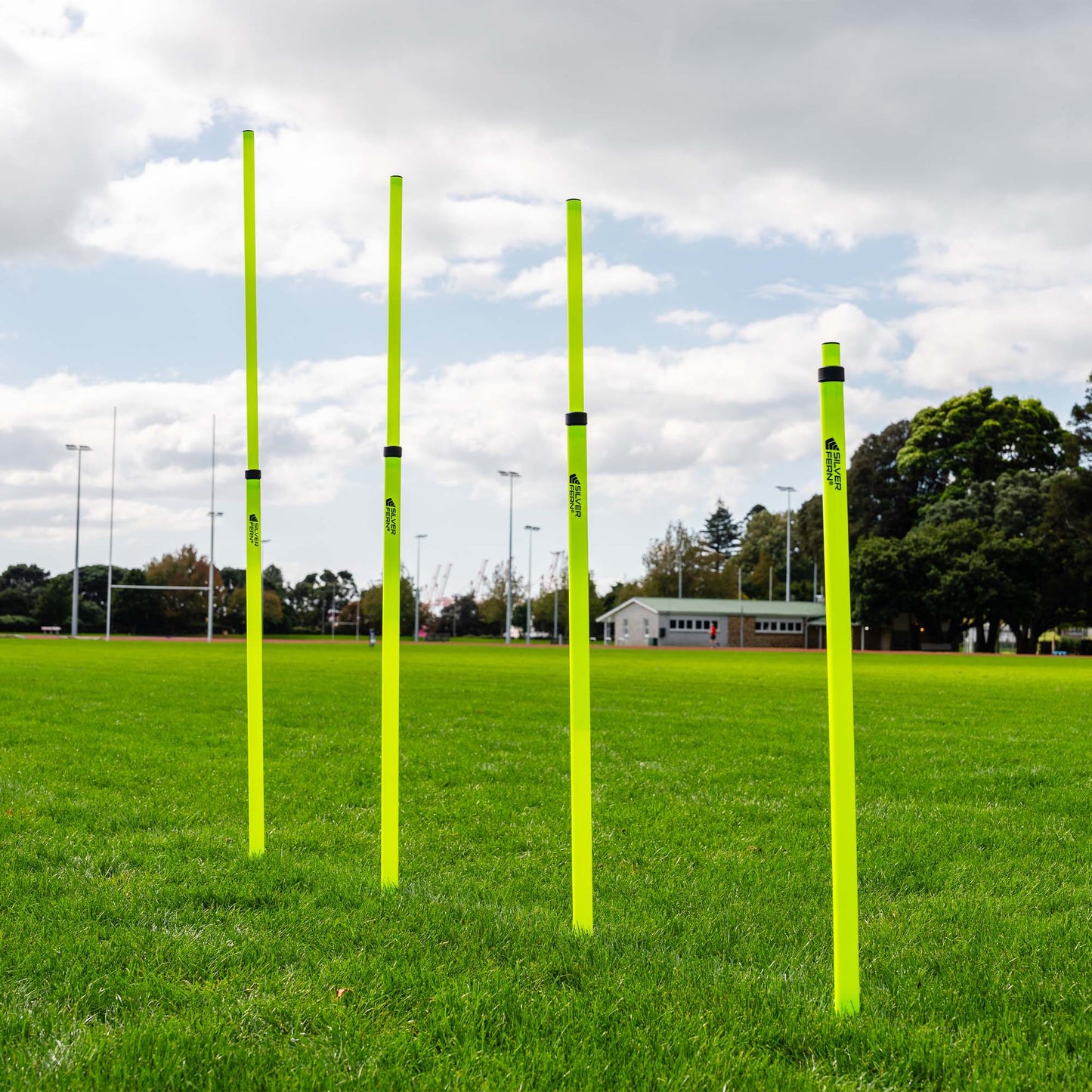 A set of Telescopic Agility Poles stacked in a grass Rugby field, showcasing different height points.