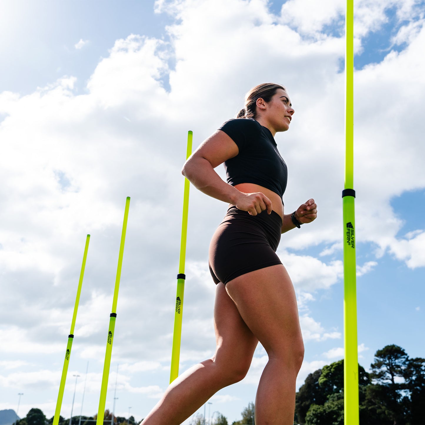 A set of Telescopic Agility Poles being showcased in use with an Athlete running in-between them, lifestyle shot.