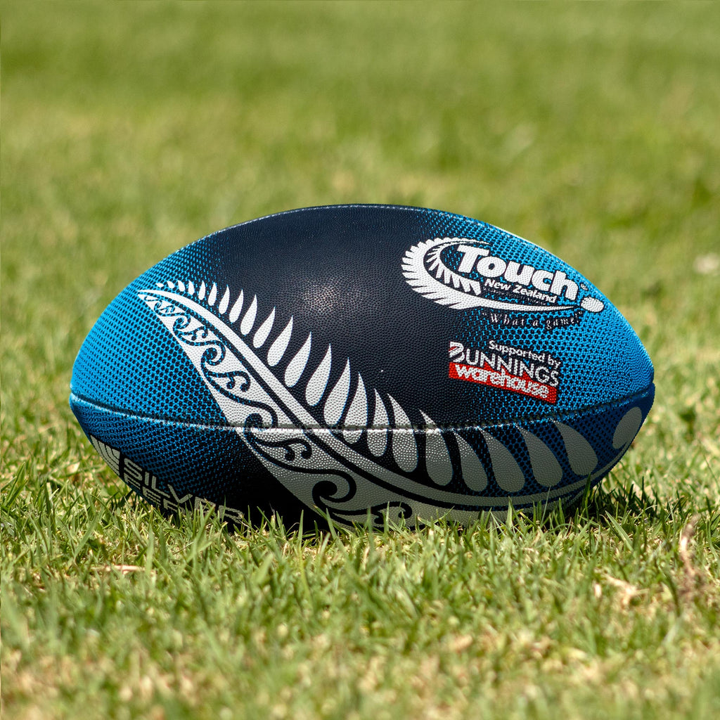 Silver Fern Touch Rugby Ball Midnight Blue Trainer, Lifestyle shot, sitting on a rugby field
